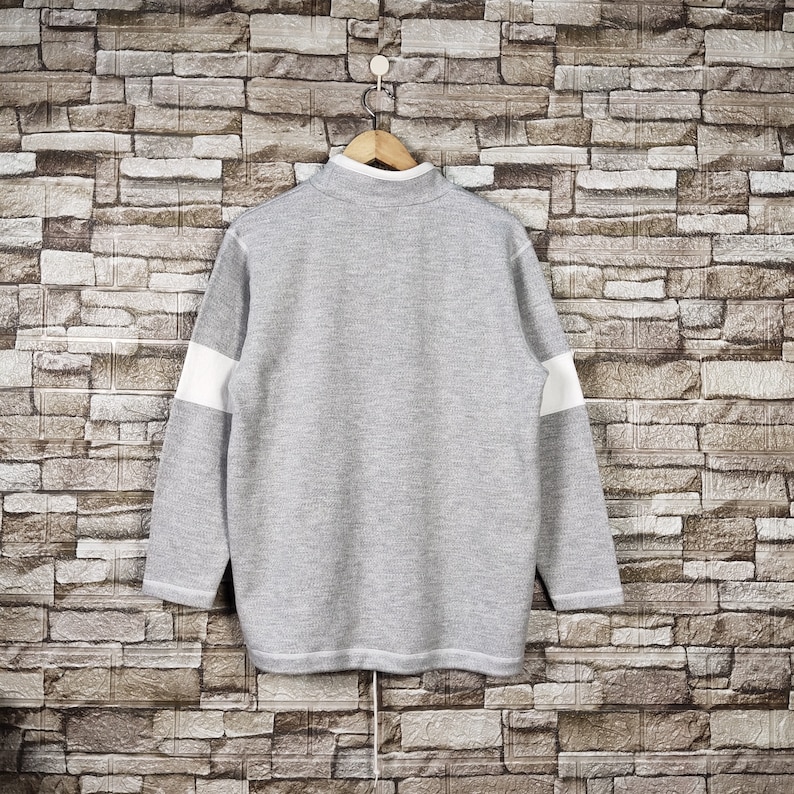 May include: A gray and white striped sweater with a long sleeve and a crew neck.