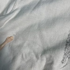 May include: Close-up of a white cotton fabric with a smooth texture. The fabric has a slight sheen and is wrinkle-free.