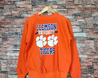 May include: Orange sweatshirt with the text "Clemson University Tigers" and a white paw print graphic.