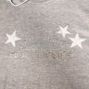 May include: Gray hooded sweatshirt with white embroidered stars and the text "sport futur courr&egrave;ges paris".