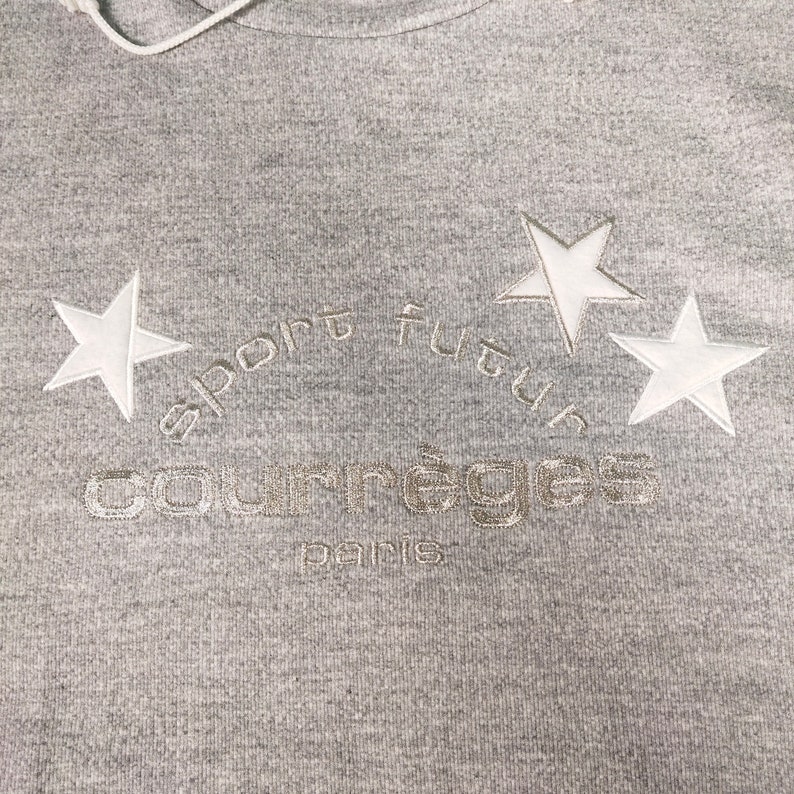 May include: Gray hooded sweatshirt with white embroidered stars and the text "sport futur courr&egrave;ges paris".