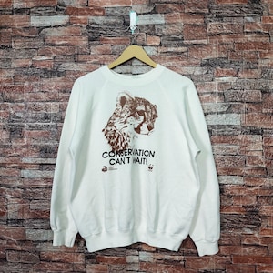 Peut inclure: Sweat-shirt blanc avec un imprimé de guépard brun et le texte "Conservation Can't Wait!" imprimé sur le devant.