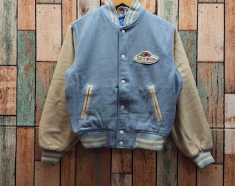 May include: Light blue varsity jacket with beige sleeves and a striped collar and cuffs. The jacket features a button-up front, two front pockets, and a patch that reads "FRUIT OF THE LOOM".
