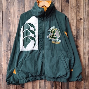May include: Green and white windbreaker jacket with a large "Daikyo Dolphins Gold Coast Australia" logo on the front. The jacket has a zipper closure and a drawstring hood.