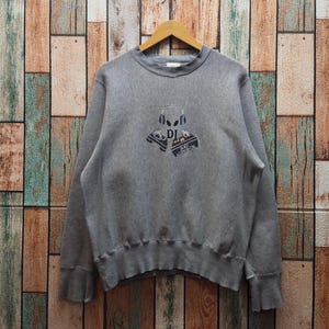 May include: A set of three ceramic mugs with a speckled, matte finish. The mugs are in shades of cream, light gray, and dark gray. Each mug has a simple, minimalist design and a rounded handle.