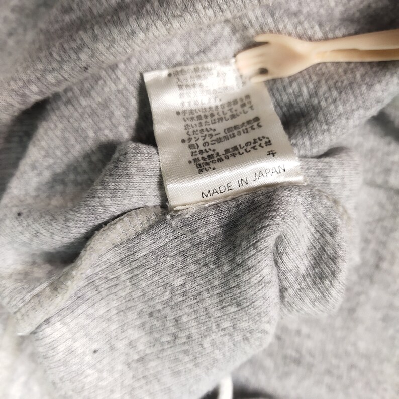 May include: A white tag with black text that reads "MADE IN JAPAN" on a gray fabric background.
