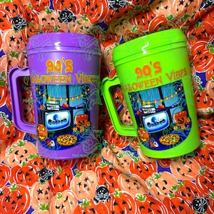 Op de afbeelding: Een paarse en een limoengroene plastic beker, elk voorzien van een handvat en een grafische print van een televisie die de tekst 'Casper' weergeeft, met de woorden '90's HALLOWEEN VIBES' in oranje letters boven het scherm.