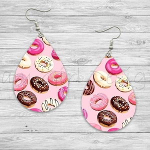 May include: A pair of pink teardrop-shaped earrings with a donut pattern. The donuts are pink, white, and brown with sprinkles and chocolate frosting.