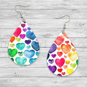 May include: A pair of teardrop-shaped earrings with a white background and a colorful watercolor heart pattern. The hearts are in shades of red, orange, yellow, green, blue, purple, and pink.