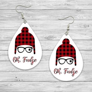 May include: A pair of white teardrop-shaped earrings with a red and black plaid pattern, a black and white illustration of a person wearing glasses and a hat, and the text "Oh, Fudge".