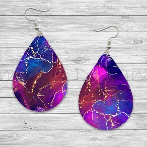 May include: A pair of teardrop-shaped earrings with a purple, blue, and gold abstract design. The earrings have silver hooks.