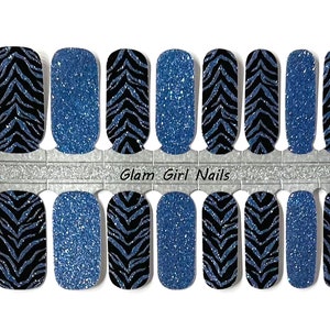 May include: A sheet of 10 blue and black nail wraps with a zebra print design. The nail wraps are arranged in two rows of five. The text "Glam Girl Nails" is printed on the sheet.