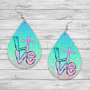 May include: A pair of teardrop-shaped earrings with a turquoise and pink ombre design. The earrings feature a cross and the word "Love" in a colorful, glittery font.