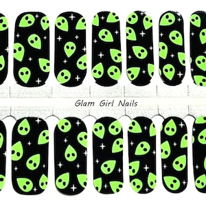 May include: Set of 10 nail wraps with a black background and a repeating pattern of green alien faces and white stars.  Glam Girl Nails.