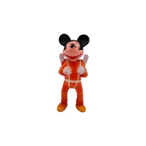 May include: A small plastic figurine of Mickey Mouse wearing an orange jumpsuit with white accents and a white parachute on his back.
