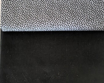 May include: Two fabric swatches. The top swatch is light gray with a pattern of small black dots. The bottom swatch is black and has a ribbed texture. The fabrics are folded over each other.