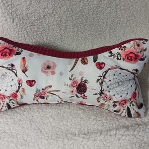 Op de afbeelding: Een wit kussen met een bordeauxrode bies en een bloemenpatroon met droomvangers, veren en rozen.