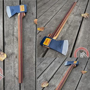 May include: A felling axe with a dark blue metal head featuring the text ACDOR on a yellow label. The handle is constructed from multiple layers of laminated wood in shades of brown, red, and tan, creating a striped pattern along the length.