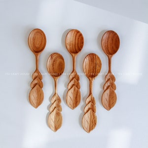 May include: Set of six wooden spoons with leaf carvings. The spoons are a light brown color and have a rounded bowl. The leaf carvings are detailed and intricate.