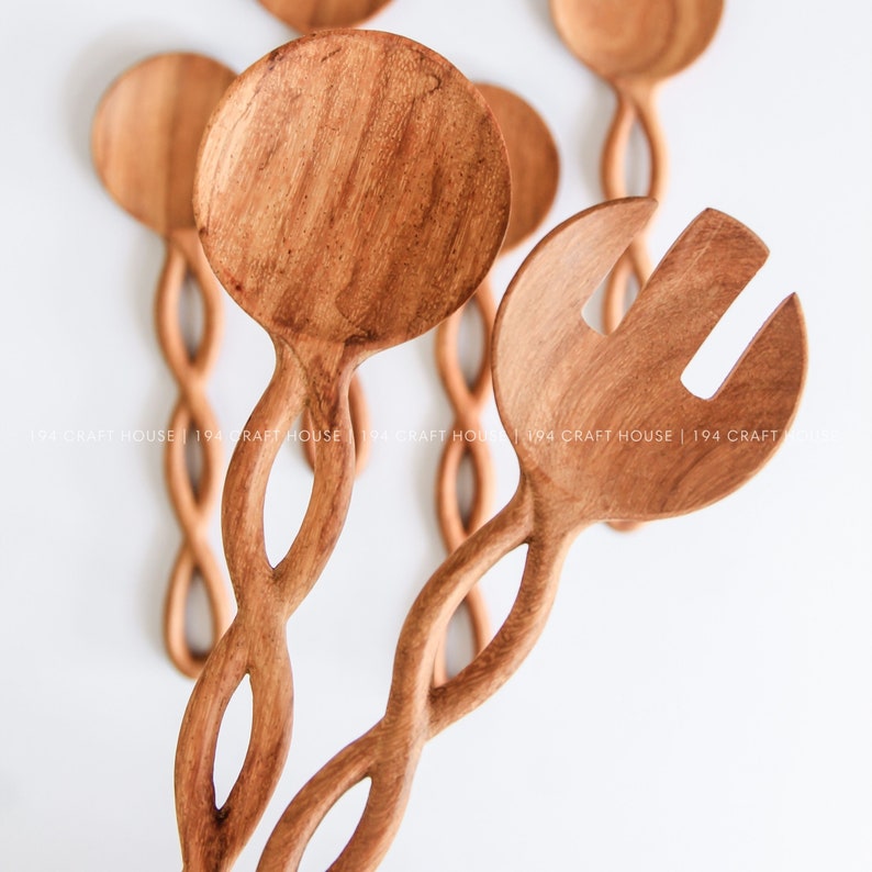 May include: A set of two wooden salad servers with a twisted handle design. The servers are made of natural wood and have a light brown color.
