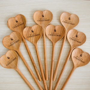 Può includere: Nove cucchiai di legno a forma di cuore con il testo "Buon Natale" e un design di renna inciso su ogni cucchiaio.