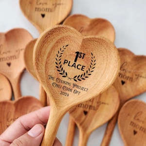 May include: Wooden heart-shaped spoons with engraved text. One spoon reads "1st Place The Cooking Project Chili Cook Off 2024". Other spoons read "Love you Mom".