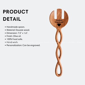 May include: A wooden salad serving spoon with a twisted handle and a fork at the top. The spoon is 7.5 inches long and 1.6 inches wide. The spoon is made of Doussie wood and has an olive oil finish. The spoon is 100% food safe and can be hand washed. The spoon is engraved with the words "Custom Engraved" and a heart.