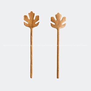 May include: Two wooden salad servers with leaf-shaped heads. The servers are made of natural wood and have a light brown colour.