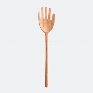 May include: A wooden hand-shaped kitchen utensil with a long handle. The utensil is made of natural wood and has a light brown color.