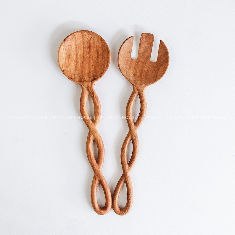 May include: A set of two wooden salad servers with twisted handles. The servers are made of natural wood and have a light brown color.
