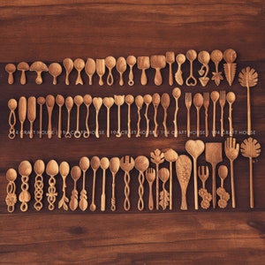 Op de afbeelding: Een verzameling handgemaakte houten lepels en keukengerei, waaronder lepels, vorken en spatels, gerangschikt op een donker houten oppervlak. Het keukengerei heeft verschillende ontwerpen, zoals bladeren en hartvormen. De tekst "194 CRAFT HOUSE" is zichtbaar.