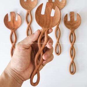 May include: A set of five wooden salad servers with twisted handles. The servers have a spoon-like head with two prongs.