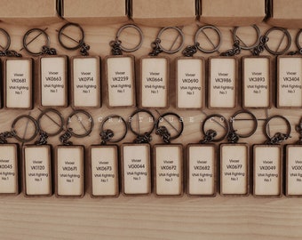 May include: A collection of wooden keychains with black metal key rings. Each keychain features a rectangular wooden tag with the text "Vivoer" and a unique code, followed by "VN4 Fighting" and "No. 1".