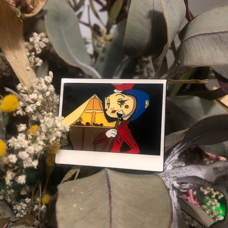 Puede incluir: Un personaje de dibujos animados con un casco azul y una chaqueta roja sostiene un palo. El personaje est&aacute; de pie frente a una l&aacute;mpara con una pantalla amarilla. La imagen est&aacute; en un marco blanco con un borde negro.