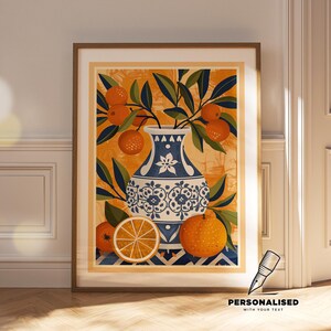 May include: A framed art print featuring a blue and white patterned vase filled with orange branches and oranges. The background is a textured orange and yellow pattern. A sliced orange is in the foreground. The print is in a wooden frame.