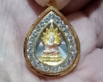 以下が含まれることがあります： 透明な石の中心に金の仏像の画像が描かれた、涙の形をした金のペンダント。ペンダントは、小さな透明な石の縁で囲まれています。