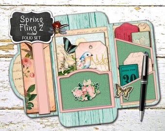 May include: A printable folio set with a spring theme. The set includes a variety of decorative elements, including butterflies, flowers, and a bird. The text "Spring Fling 2 Printable Folio Set" is printed on a black chalkboard.