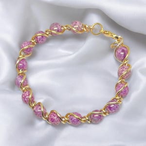 May include: A gold wire wrapped bracelet with pink and white agate beads.