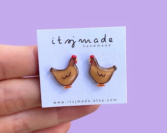 May include: A pair of brown chicken stud earrings with red combs. The earrings are on a white card with the text "itsjmade handmade" and "www.itsjmade.etsy.com".