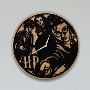 Könnte beinhalten: Eine Holzuhr mit einer schwarzen Silhouette von Harry Potter, Ron Weasley und Hermine Granger. Das Zifferblatt der Uhr zeigt die Buchstaben "HP" und einen Zauberstab.