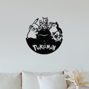 May include: Black vinyl record clock featuring Pokemon characters, including Pikachu, Meowth, and Jigglypuff. The clock face is white with black hands and black numbers. The word "Pokemon" is written in white on the black vinyl record.