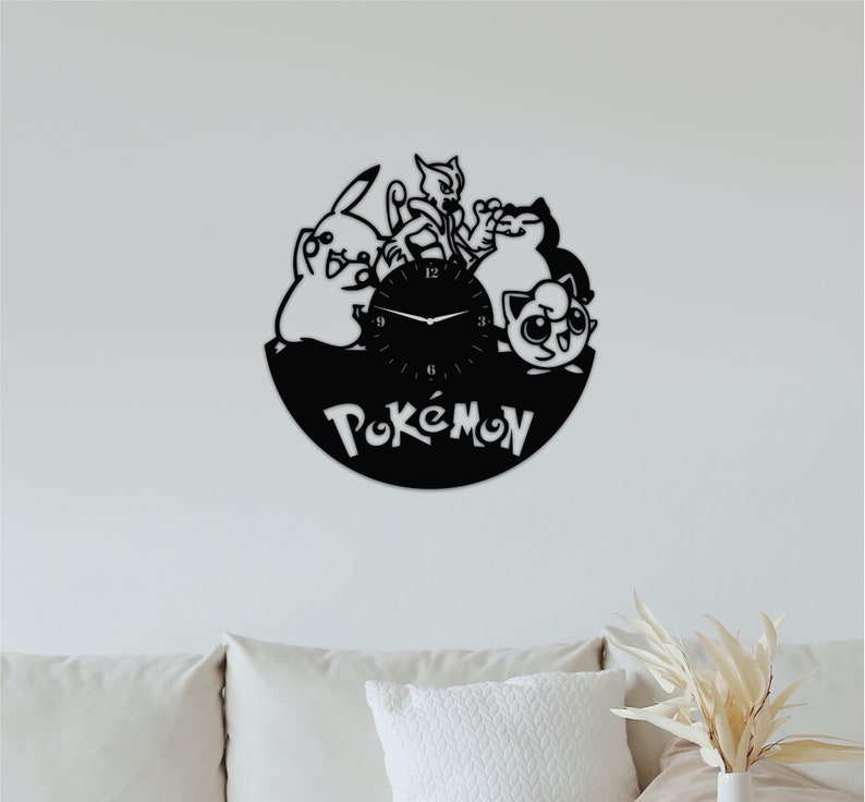 May include: Black vinyl record clock featuring Pokemon characters, including Pikachu, Meowth, and Jigglypuff. The clock face is white with black hands and black numbers. The word "Pokemon" is written in white on the black vinyl record.