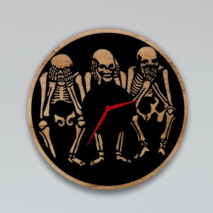 May include: A wooden clock with a black background featuring three skeletons in the "See No Evil, Hear No Evil, Speak No Evil" pose. The clock hands are red.