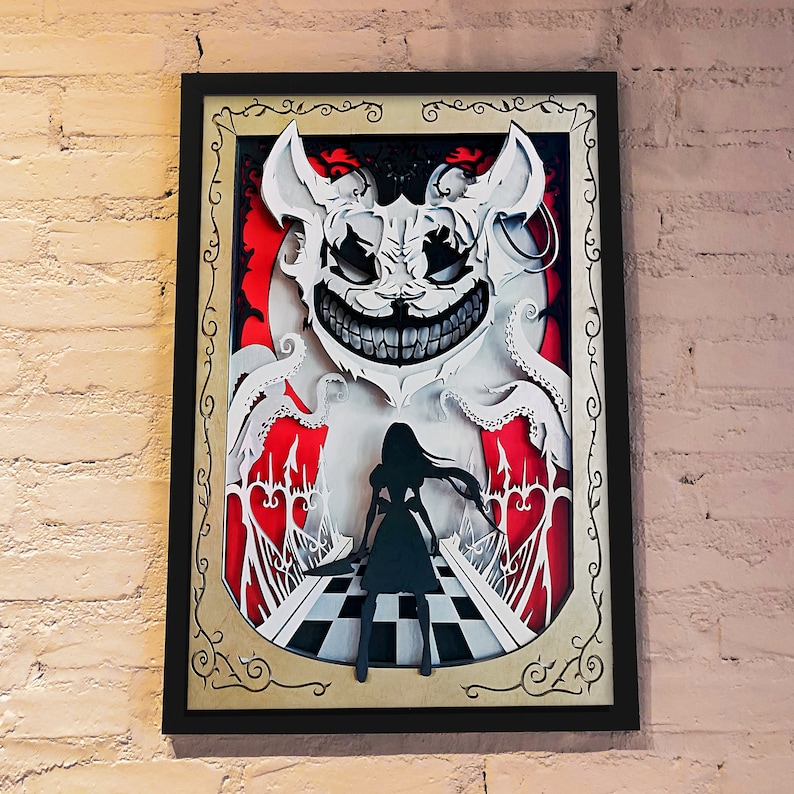 May include: A framed papercraft artwork depicting a white, grinning monster with a black silhouette of a girl standing in front of it. The artwork is set against a red and white checkered background.