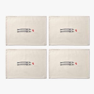 Puede incluir: Cuatro manteles individuales rectangulares de color blanquecino. Cada uno presenta un par de peces azul oscuro estilizados con un peque&ntilde;o coraz&oacute;n rojo. Los peces est&aacute;n dibujados con l&iacute;neas simples, creando un dise&ntilde;o minimalista.