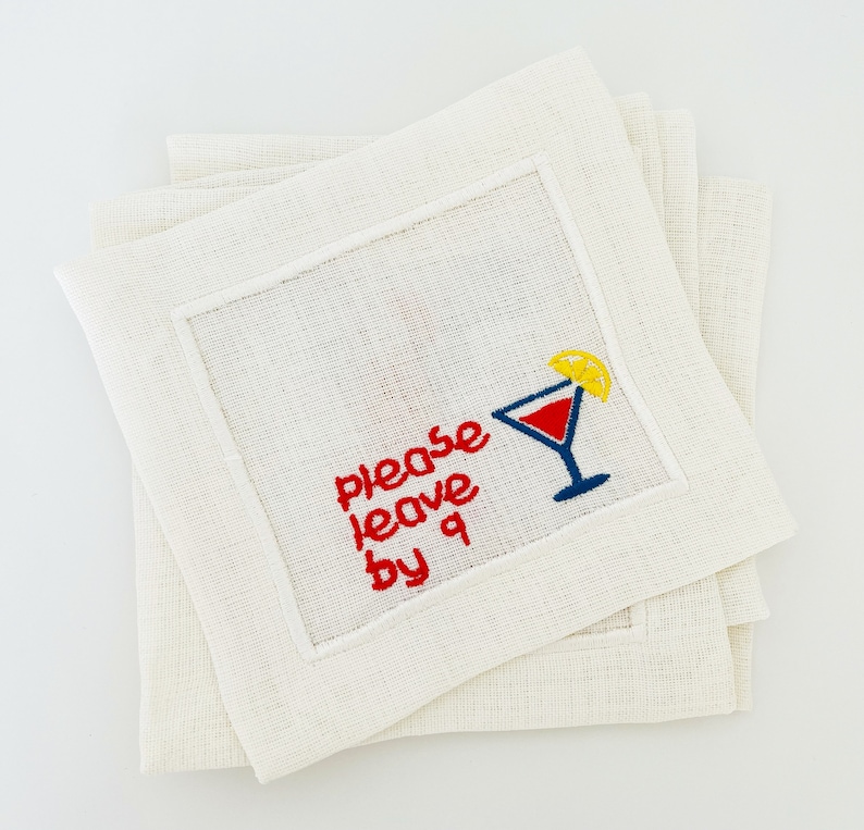 Puede incluir: Juego de cuatro servilletas de c&oacute;ctel de lino blanco con bordado rojo que dice "Please leave by 9" y una copa de c&oacute;ctel roja y azul con una rodaja de lim&oacute;n amarilla.