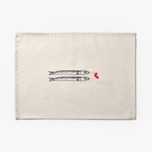 Puede incluir: Mantel individual color crema con un dise&ntilde;o caprichoso de dos peces estilizados y un coraz&oacute;n rojo. Los peces est&aacute;n dibujados en negro, contrastando con el fondo neutro. Una adici&oacute;n encantadora a cualquier mesa.