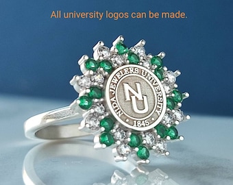 Könnte beinhalten: Ein silberner Ring mit einer grünen und weißen Steinbesetzung. Der Ring hat ein kreisförmiges Design mit den Worten "Nida Jewlers University" und "1845" um ein großes "NU" in der Mitte.