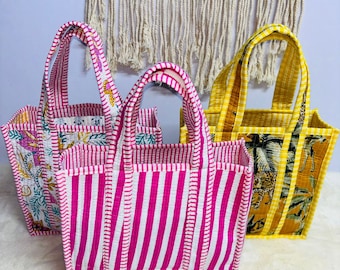 May include: Three colorful tote bags with patterned designs. One bag features pink and white stripes, another has a floral pattern, and the third displays a yellow and brown animal print. Each bag has a matching handle.