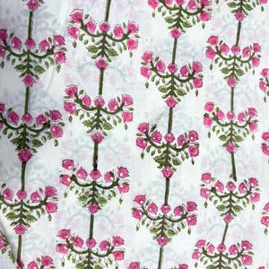 Pu&ograve; includere: Tessuto bianco con un motivo ripetuto di bouquet floreali rosa e steli verdi. Il motivo floreale &egrave; uniformemente distanziato, creando un motivo simmetrico. Il tessuto sembra essere di cotone o un materiale leggero simile, adatto a vari progetti.